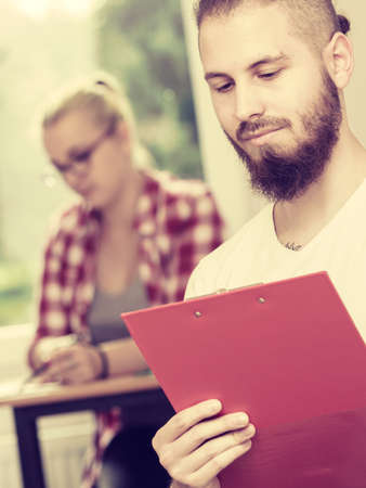 Education, high school, teamwork and people concept - student boy with notebook sitting in front of students her group mates in classroomの写真素材
