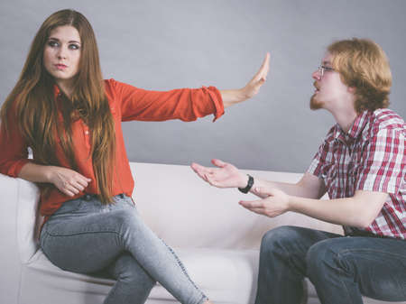 Man begging woman who is sitting on sofa for forgiveness. Couple after fight or argue. Female...