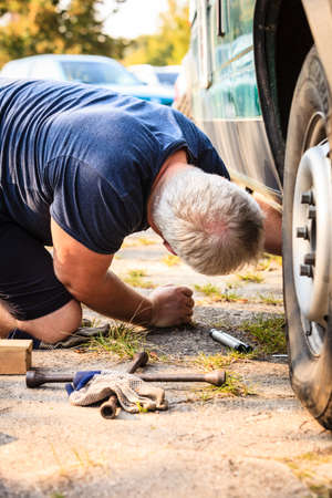 Casual man working under car fixing auto parts. Transportation, broken vehicles problems .