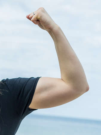 Unrecognizable woman showing her biceps arm muscle. Weight lifting progress, exercising concept.の写真素材