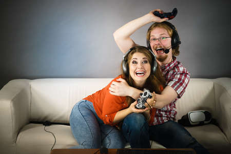 Couple enjoying leisure time by playing video games together, man and woman being emotional by game.の写真素材