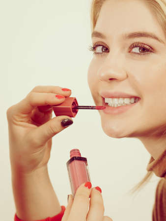 Young adult woman applying lipstick or lip gloss on her lips getting her make up done.の写真素材