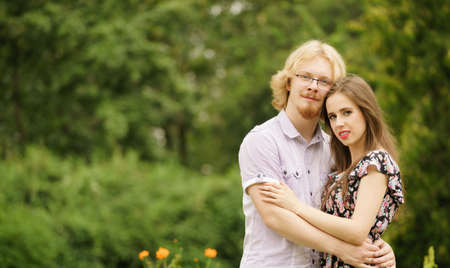 Happy joyful teen couple hugging outdoor in green park during beautiful summer weather.