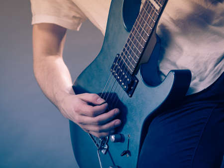 Close up of man playing on electric guitar during gig or at music studio. Musical instruments, passion and hobby concept.の写真素材