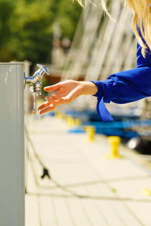 Woman cleaning washing her hands outdoor in marine water dispenser. Hygiene concept.