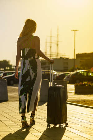 Traveling holidays concept. Fashion woman with suitcase in travel location by sea portの写真素材