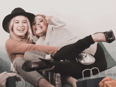 Two happy joyful women having fun after shopping, picking outfit in closet. Female friends fooling around.の写真素材