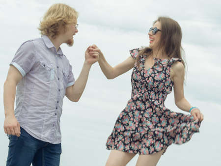 Joyful couple having fun outdoor. Young man and woman dancing jumping together during date.の写真素材