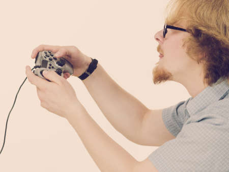 Nerd geek young adult man playing on the video console holding game pad. Gaming gamers concept.