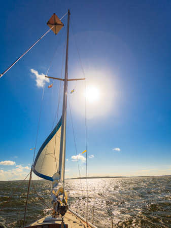 Yachting on sail boat during sunny summer weather on calm blue sea water. Sporty transportation...