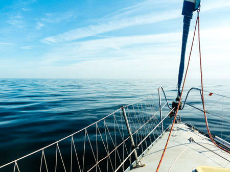 Yachting on sail boat during sunny summer weather on calm sea water. Sporty transportation concept.の写真素材