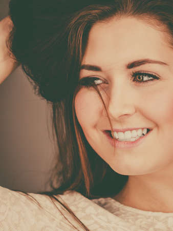 Happy positive woman with long brown hair presenting her healthy hairdo. Haircare concept. Studio shot on grey backgorund.の写真素材