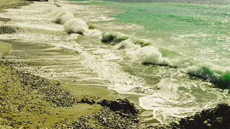 Beautiful sandy beach coastline next to sea edge with water waving and splashing during summertime...