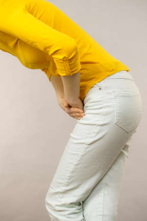 Closeup young sick woman with hands holding pressing her crotch lower abdomen. Medical or...