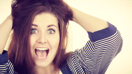 Attractive woman with dark brown hair having shocked amazed face expression with wide open mouth...