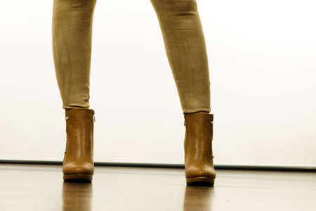 Close up of woman wearing brown suede slim fit trousers and high heels autumnal boots shoes.