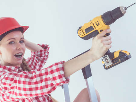 Woman having troubles with using construction drill. Female does not know how to use driller.の写真素材