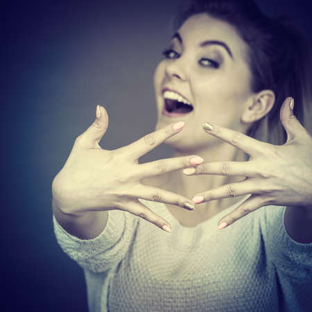 Happy proud young woman showing her hands in front of her face, studio shot grey background.