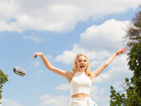 Cheerful female fashion model presenting casual elegant outfit. Woman holding purse bag having fun...