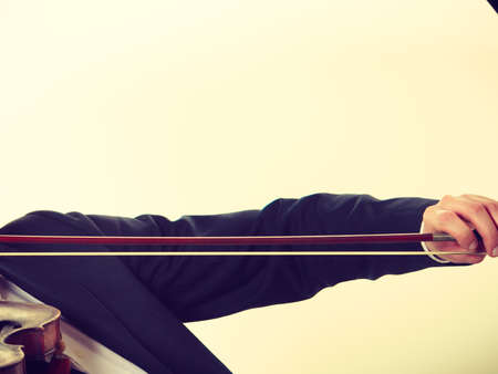 Music passion, hobby concept. Man dressed elegantly playing on wooden violin, close up on bow. Studio shot on light backgroundの写真素材