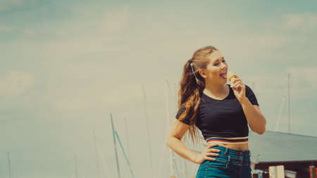 Happy funny young woman with long brown hair eating ice cream having fun.