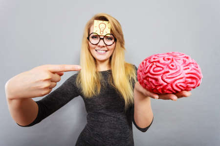 Weird blonde woman holding brain having something on mind, thinking of idea.の写真素材