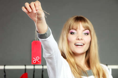 Good shopping sale concept. Blonde fashionable woman choosing clothes holding discount red label...
