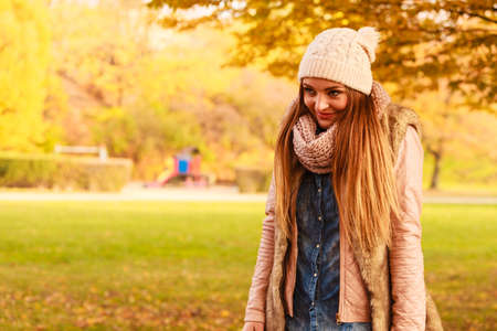 Autumn season. Smiling attractive woman relaxing outdoors in autumnal park, enjoying sunny day....