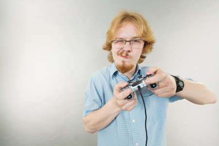 Nerd geek young adult man playing on the video console holding game pad. Gaming gamers concept.の写真素材