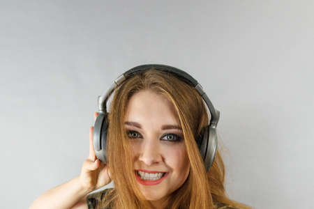 Cheerful teenage woman listening to music through big headphones having fun. Bizarre crazy close up.