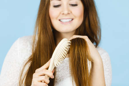 Haircare and morning hairstyling concept. Happy woman brushing her long dark brown hair