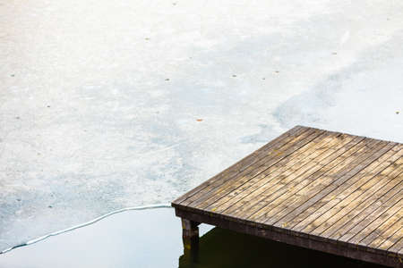 Winter weather, freezing lake concept. Closeup of wooden bridge platform on frozen water