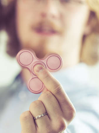 Man being fascinated by pink fidget spinner. Social media trend, funny toy concept.の写真素材
