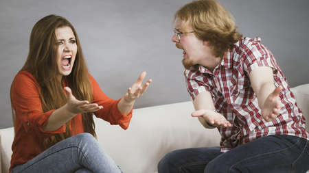 Man and woman having horrible fight while sitting on sofa. Friendship, couple breakup difficulties...