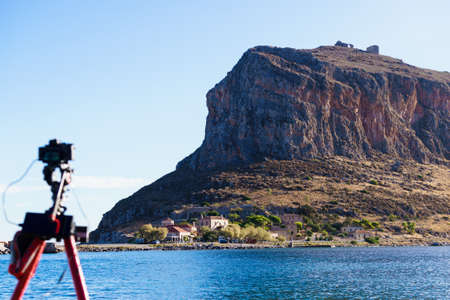 Professional camera on tripod taking picture film video from Monemvasia island, Greece Peloponnese Lakoniaの写真素材