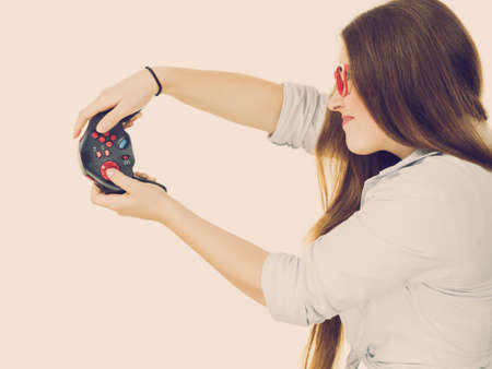 Young adult emotional woman from profile playing on the video console holding game pad. Gaming gamers concept.の写真素材