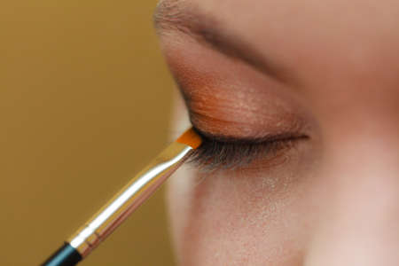 Visage concept. Close up woman getting make up on eyelids. Applying eyeshadow with brush, closed eyes.の写真素材