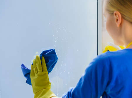 Woman using cloth cleaning detergent to clean window glass. House clean products, household care...