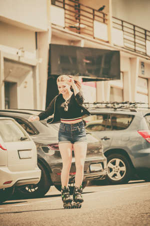 Teenage woman girl riding roller skates during summertime through city having great time.の写真素材
