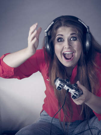 Nerd geek young adult women playing on the video console holding game pad being shocked Gaming...