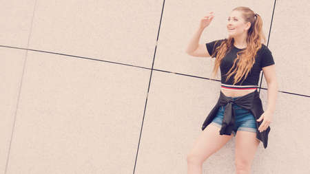 Young teenage woman wearing denim shorts and black crop top. Female presenting fashionable summer...