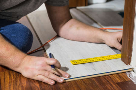 Construcion worker measuring floor panels using ruler and pencil. Home renovation concept.の写真素材