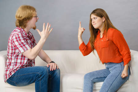 Man and woman having horrible fight while sitting on sofa. Friendship, couple breakup difficulties...