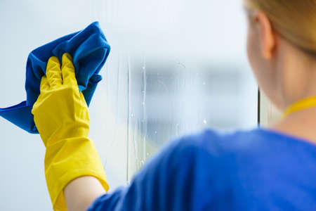 Woman using cloth cleaning detergent to clean window glass. House clean products, household care...