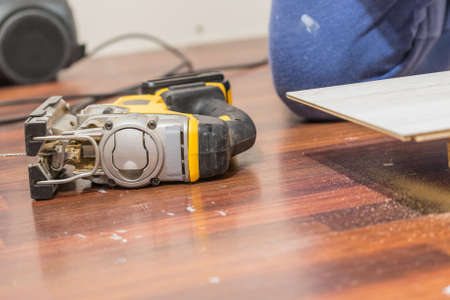 Person cutting floor panels using industrial tool to cut perfect shape for instalation. Home renovation concept.の写真素材