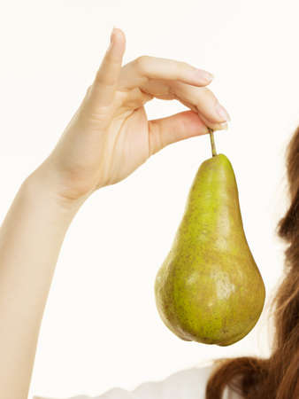 Female hand holding green pear fruit, on white. Healthy dieting, vegan food, vitamins immunity concept.の写真素材