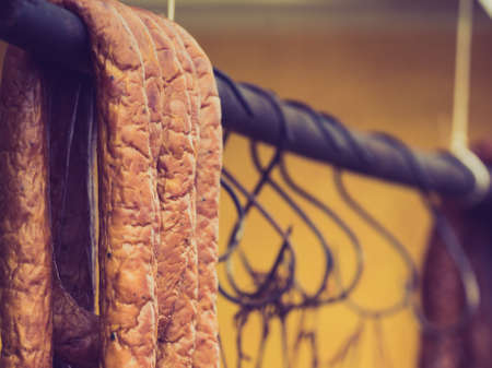 Traditional food. Smoked sausages ham meat hanging in domestic smokehouse on strings.の写真素材