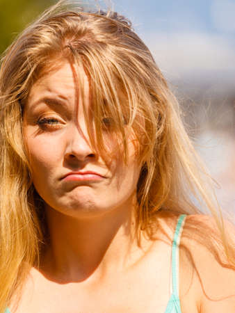 Face expressions concept. Very sad looking blonde woman portrait in sunlight. Outdoor shot