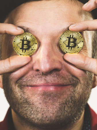 Adult man having bitcoin coin as pince nez in eye. Crypto internet currency banking concept.の写真素材
