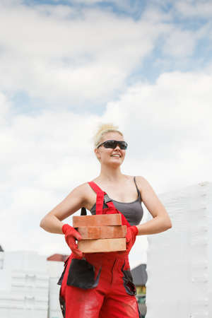 Strong pretty woman working on construction site, building house, installing bricks. Industrial work concept.の写真素材